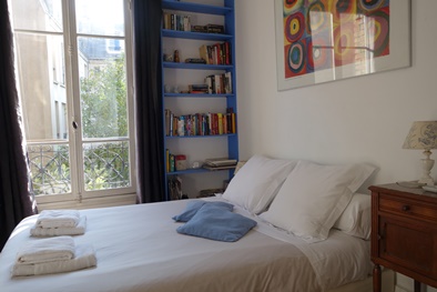 The bedroom features a large double bed and full-length windows